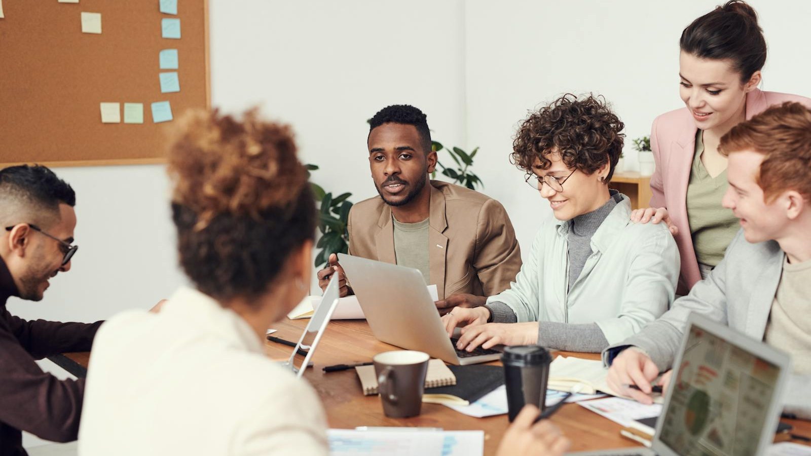Equipo de trabajo revisando opciones en una mesa con portátiles y gráficos impresos